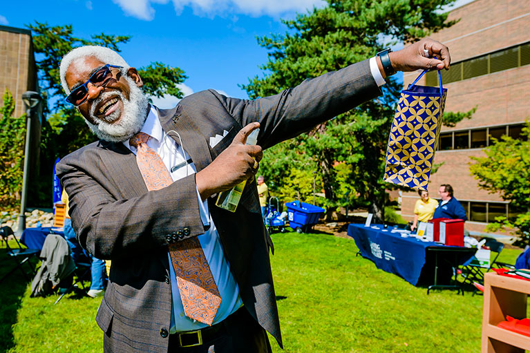 lcc faculty member striking a pose while holding a gift bag from an lcc event